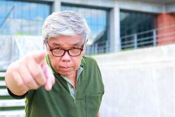 An elderly Asian man studying in university wearing eyeglasses and pointing his finger forward. adult education concept. copy space