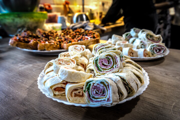 Lavash roll with red fish, cheese, ham and spinach on white plate