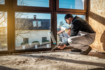 Worker is applying polyurethane foam to fill gap between sash and window frame - obrazy, fototapety, plakaty