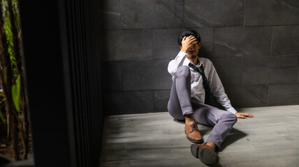 Portrait man stressed sad and tired from over working. Overworked and worried. male business man worker sitting on the floor and dark background