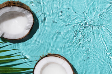 Summer background with coconuts on water background with water splashes. Creative summer background for design. Coconut cosmetics.