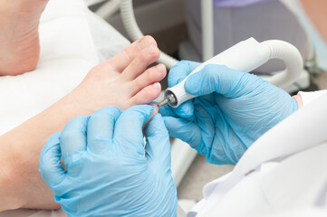 Medical pedicure. Professional pedicure in the salon. Young girl makes a pedicure in the background...