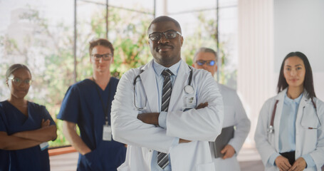 Fototapeta premium Team Portrait of a Female and Male Successful Diverse Medical Healthcare Professionals Standing as a Group in a Modern Hospital Office. African American Doctor Standing Closer to Camera