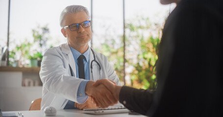 Caucasian Doctor Speaking to a Young Man During a Consultation in Health Clinic. Physician in White Lab Coat Shaking Hands with Patient After Agreeing on Suggested Clinical Treatment