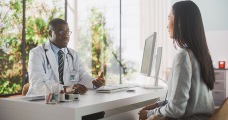 African Physician in Glasses Prescribing Medicine for a Female Patient and Listening to Her Feedback During Consultation in a Health Clinic. Doctor in Lab Coat Sitting Behind a Desk in Hospital