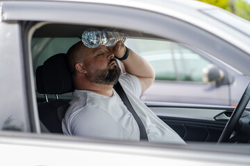 Overweight man drives car with broken air conditioner in hot summer weather. Weary male presses...