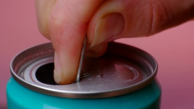 Opening soda or beer can macro close up of can pull tab, hand open lemonade, refreshment. High quality 4k footage. With my fingers I open a blue tin can with a drink in the pink background close-up