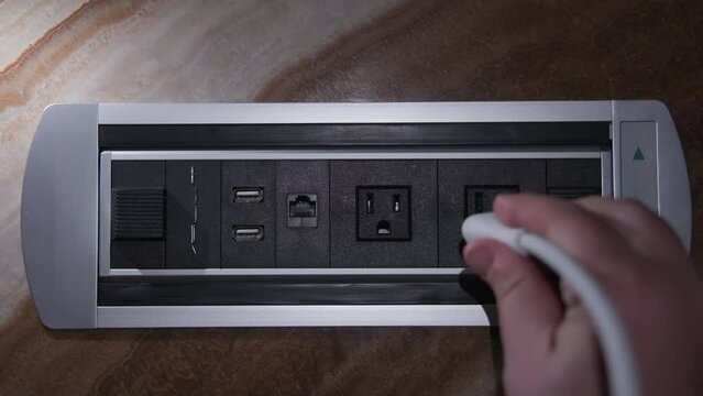 Close-up of a hand plugging cable in power outlet. Charging port socket. Modern convenient multi-port usb, socket charger for different devices. Electrical mobile phone charger. High quality 4k