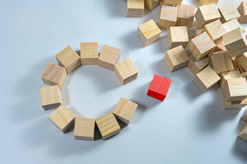 Many wooden cubes, some of them together forming a circle with a gap, one in red color is ready to complete the team, light blue background, copy space, selected focus