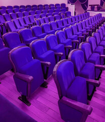 An empty modern cinema or conference room with rows of chairs, neon tinting