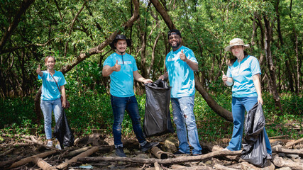 Volunteers clean discarded garbage in the forest park area. Group of happy people collecting plastic trashand and cleaning area. Environmental protection project.