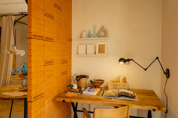 Interior view of workspace with wooden table, chair and lamp in stylish studio apartement