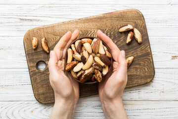 Woman hands holding a wooden bowl with brazil or bertholletia nuts. Healthy food and snack....
