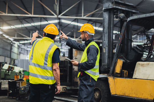 Two maintenance engineers inspect system with  computer. They work industry factory