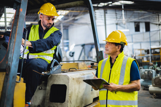warehouse worker talking with forklift operator in factory