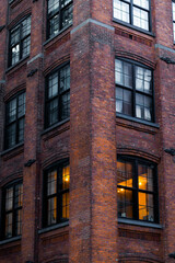Apartments in the corner of the street in New York City. Brick building with windows and some lights on