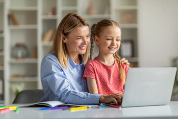 Online Education. Smiling Mother And Her Little Daughter Using Laptop At Home