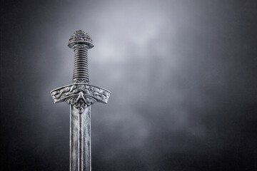 Medieval sword over dark misty background