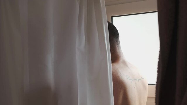 young man takes shower at home, water consumption plus daily hygiene
