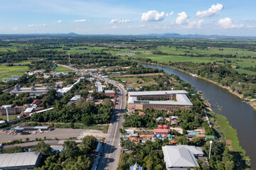 Top view of the Sakae Krang River, Uthai Thani Province where both sides of river are filled with lush green trees. There are community near waterside.