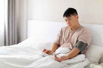 Worried asian man doing morning checkup after waking up