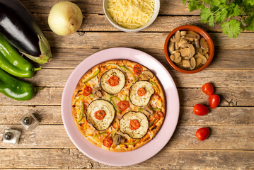 Obraz na płótnie Canvas Vegetable pizza for vegetarians ready to eat, with eggplant, pepper, cherry tomato, onion and mushroom, top view.