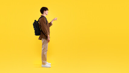 Fototapeta na wymiar Student Guy Pointing Finger At Empty Space On Yellow Background
