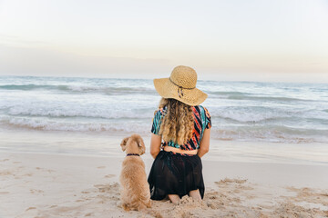 girl with her puppy in front of the beach
