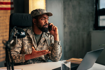 Soldier speaking on cellphone in office.