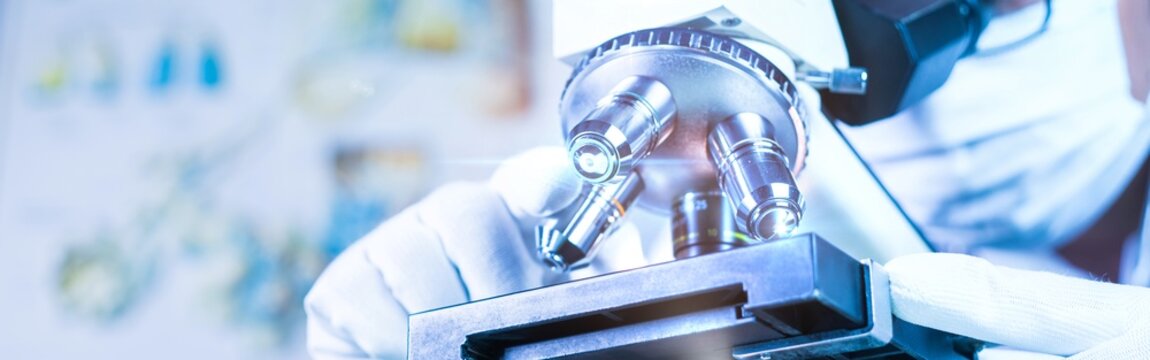 Biological scientist looking at  samples by using microscope doing research for new vaccine in pharmaceutical labolatory