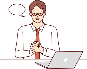 Businessman is sitting at table with laptop and looking at camera recording business training