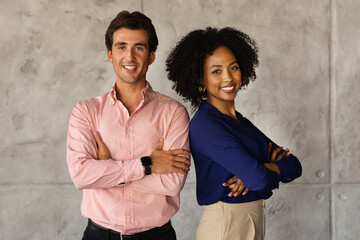Two successful multicultural businesspeople standing back to back, arms crossed