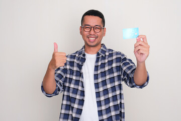 Adult Asian man smiling happy and give thumb up while showing credit card