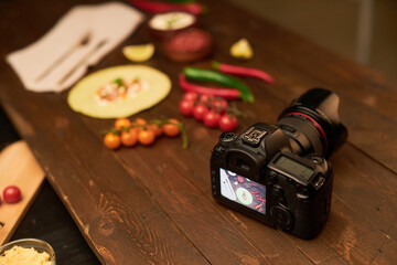 High angle view of digital camera on table to make professional photos with food in background