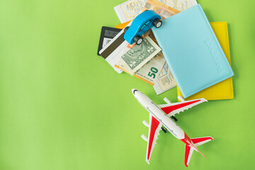 Composition from a city map with a bank card, euro, dollar banknotes, passports and a toy plane on a green background. Travel and vacation concept.