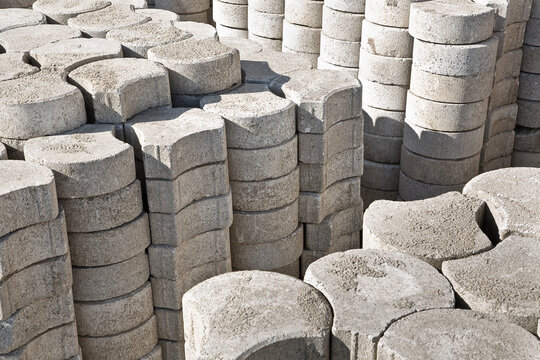 Stack of concrete self locking flooring blocks in curved shape on wooden pallet in a construction site - used in construction industry to create permeable floors to rain water on a layer of sand