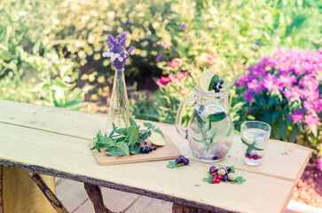 garden party table, jar with refreshment fruit lemonade, flowers, fruits and herbs