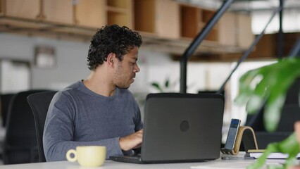 Mixed Race Businessman Using Computer in Modern Office with Colleagues. Working on Financial and Marketing Projects. Drinking Tea or Coffee from a Mug.
