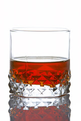 A whiskey glass reflected on white background
