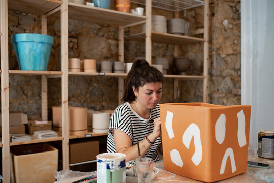 Artist painting abstract lines on terracotta pot