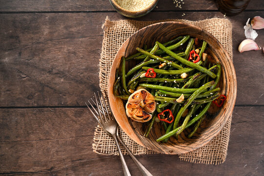 Roasted garlic green beans on wooden background. Top view, copy space