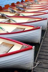 Row of docked wooden rowing boats for rent