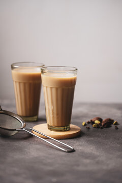 Indian masala chai tea, traditional glasses with strainer and chai spices.