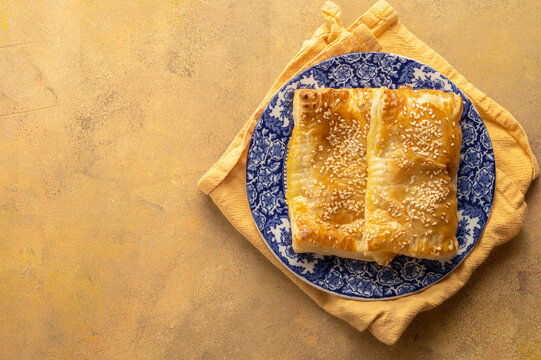 Puff pastry dough. Folded baked puff pastry pie in a plate, warm orange background