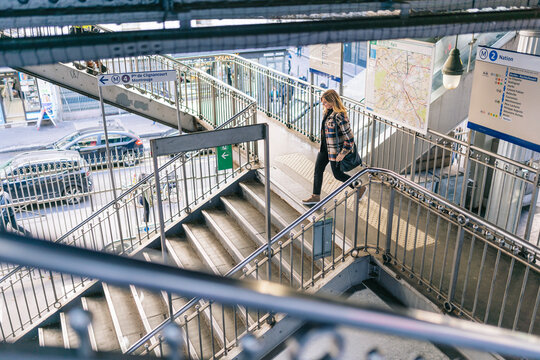 Young woman in coat climbing down on bridge steps
