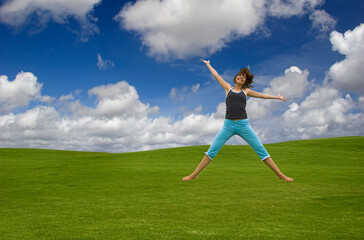Fototapeta na wymiar Beautiful happy woman jumping on a green field