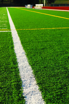 Green sports field with artificial grass and racetrack