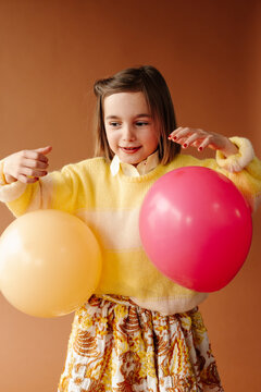 Portrait of kid playing with colored balloons at studio shoot