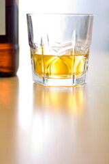 Glass of yellow whiskey and bottle on the table