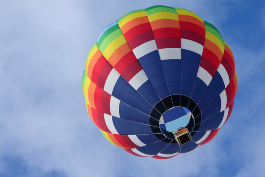 Colorful hot air balloon flying against a blue sky background